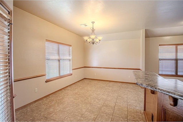 unfurnished dining area featuring a notable chandelier and a wealth of natural light