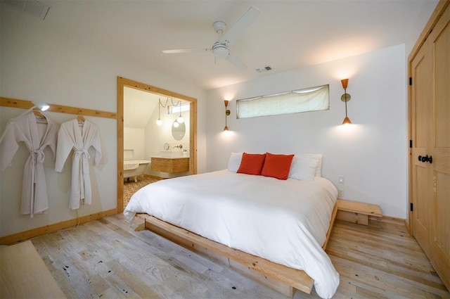 bedroom featuring light wood-type flooring, ensuite bath, ceiling fan, and vaulted ceiling