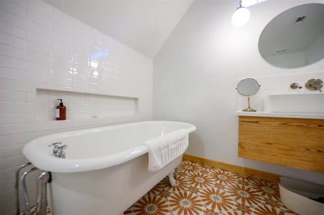 bathroom with tile patterned flooring, a tub, lofted ceiling, and sink