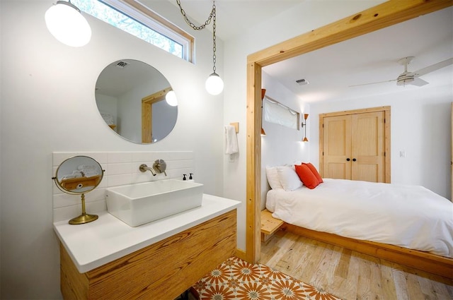 bedroom with ceiling fan, wood-type flooring, sink, and a closet