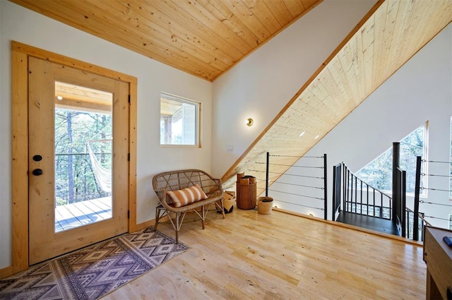 living area featuring vaulted ceiling, light wood-type flooring, and wooden ceiling