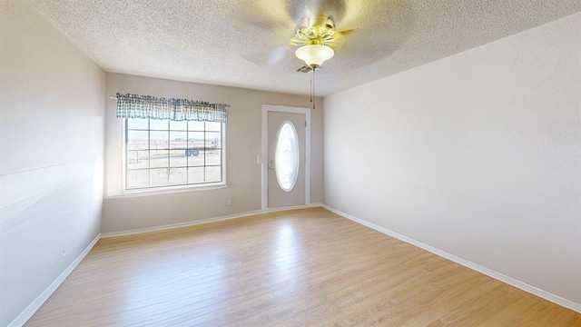 unfurnished room featuring ceiling fan, light hardwood / wood-style floors, and a textured ceiling