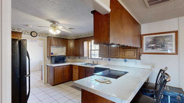 kitchen featuring kitchen peninsula, backsplash, ceiling fan, sink, and black appliances