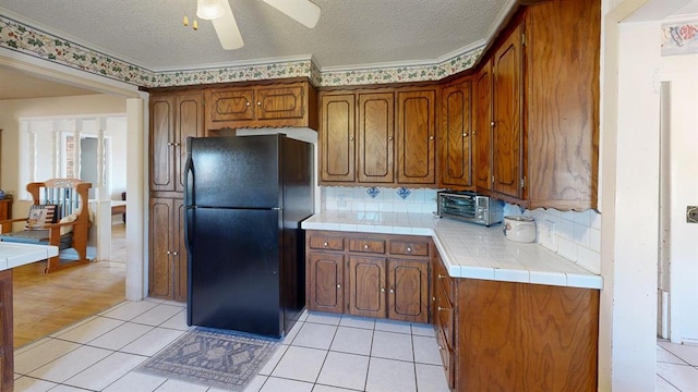 kitchen with black fridge, ornamental molding, a textured ceiling, and light wood-type flooring