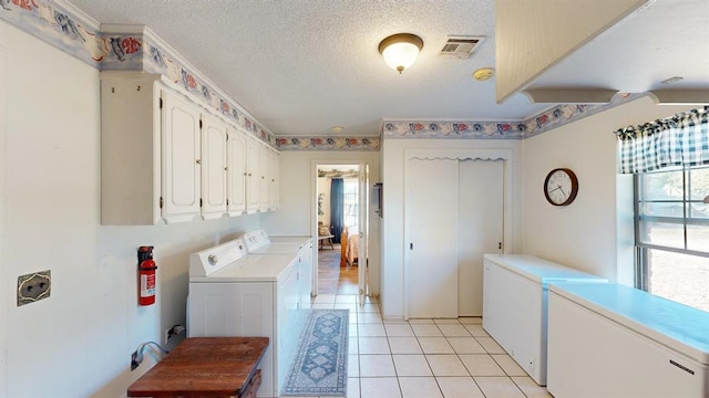 laundry room featuring light tile patterned flooring, cabinets, independent washer and dryer, and a textured ceiling