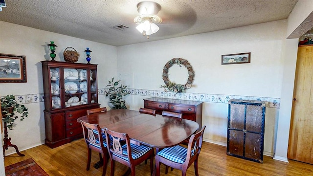 dining area with hardwood / wood-style flooring, ceiling fan, and a textured ceiling