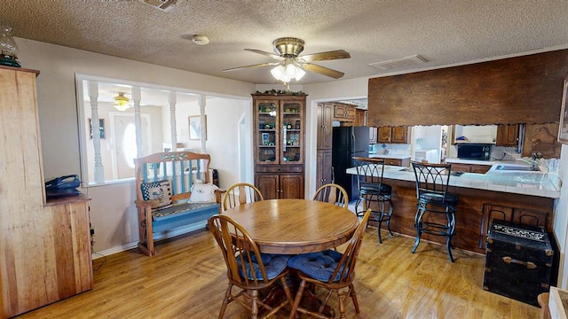 dining space with ceiling fan, light hardwood / wood-style flooring, a textured ceiling, and sink