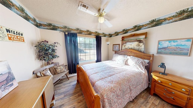 bedroom with ceiling fan, dark hardwood / wood-style flooring, and a textured ceiling