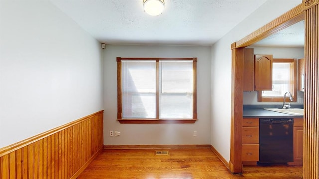 kitchen with sink, dishwasher, and light wood-type flooring