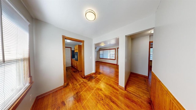 corridor featuring light wood-type flooring and vaulted ceiling