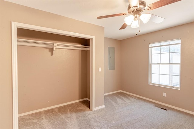 unfurnished bedroom with ceiling fan, light carpet, electric panel, and a closet