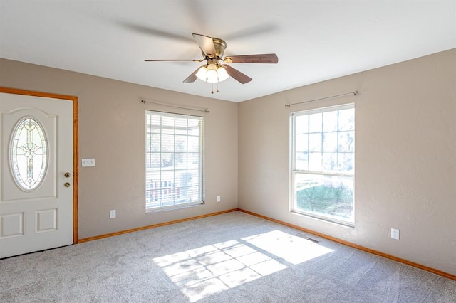 foyer featuring ceiling fan, light colored carpet, and a wealth of natural light