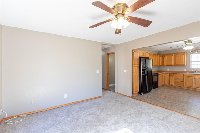 kitchen with ceiling fan, sink, black appliances, and light wood-type flooring