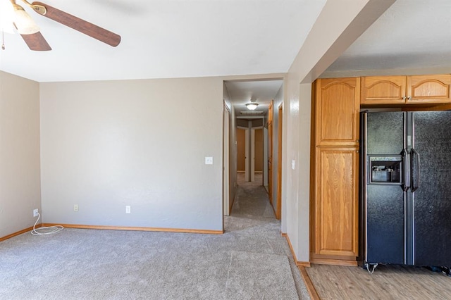 kitchen with black fridge, light brown cabinetry, ceiling fan, and light carpet