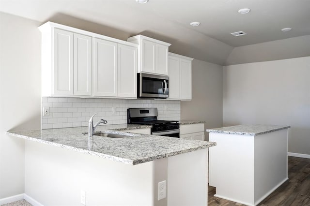 kitchen featuring kitchen peninsula, light stone countertops, stainless steel appliances, sink, and white cabinets