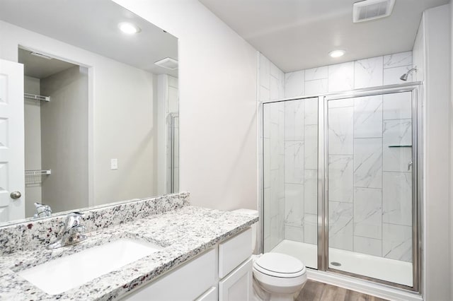 bathroom featuring wood-type flooring, vanity, toilet, and an enclosed shower