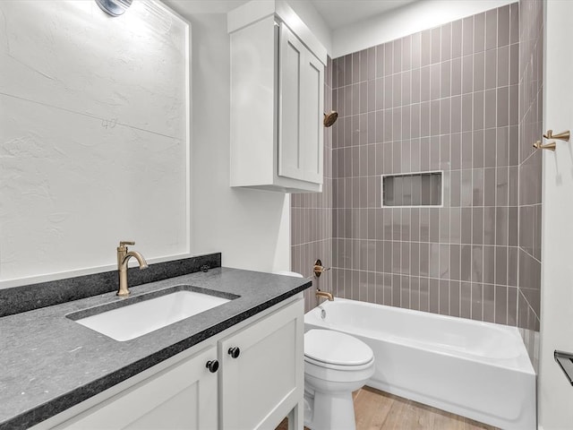 full bathroom featuring hardwood / wood-style flooring, vanity, toilet, and tiled shower / bath