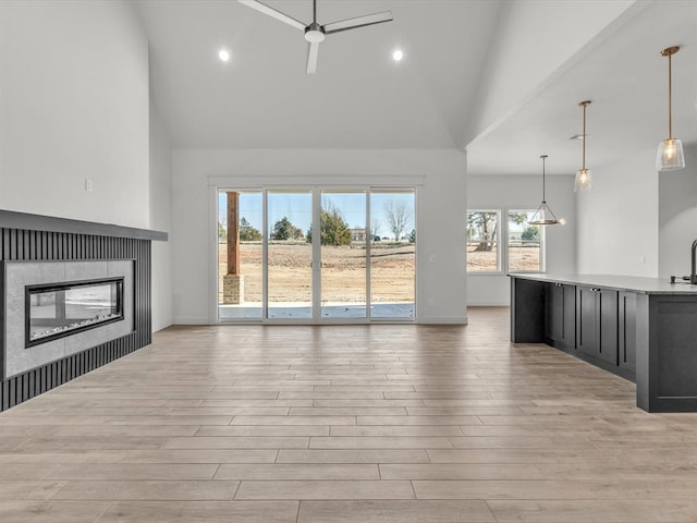 unfurnished living room with high vaulted ceiling and ceiling fan