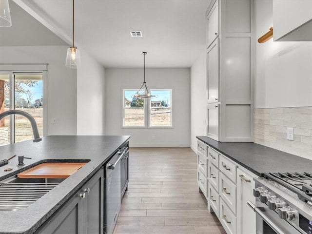 kitchen with a wealth of natural light, sink, decorative light fixtures, and appliances with stainless steel finishes