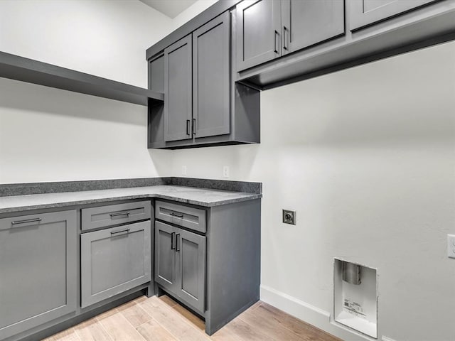 laundry room with cabinets, light wood-type flooring, and electric dryer hookup