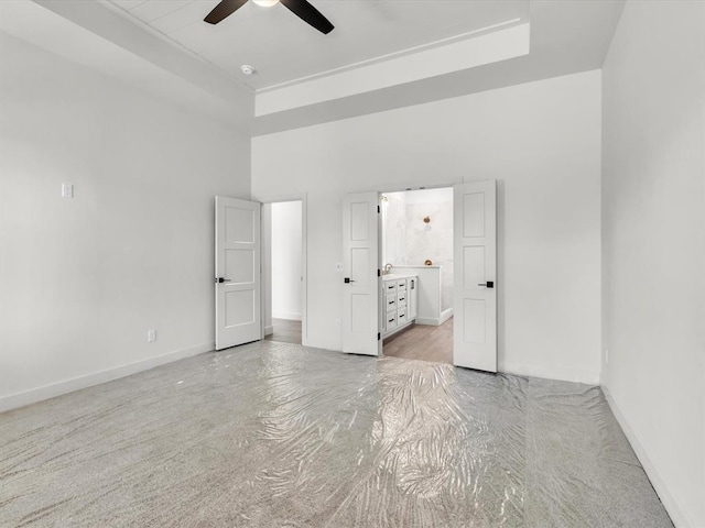 unfurnished bedroom featuring a towering ceiling, ensuite bath, and ceiling fan