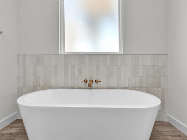 bathroom with hardwood / wood-style flooring and a bath