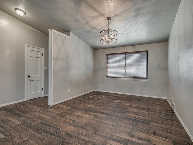 spare room featuring a textured ceiling, a chandelier, and dark hardwood / wood-style floors