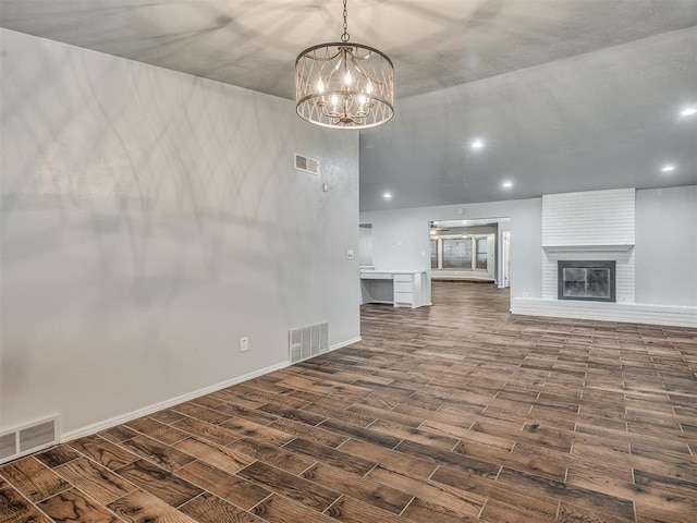 unfurnished living room featuring a fireplace, dark wood-type flooring, and a notable chandelier