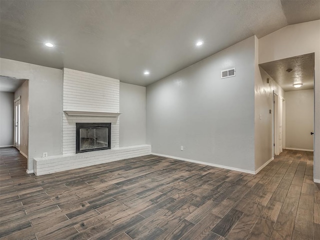 unfurnished living room with lofted ceiling, dark wood-type flooring, and a brick fireplace