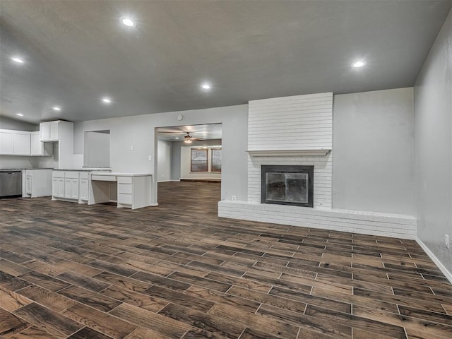 unfurnished living room with ceiling fan, dark hardwood / wood-style flooring, and a brick fireplace