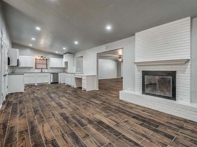 unfurnished living room featuring ceiling fan, dark hardwood / wood-style flooring, vaulted ceiling, and a brick fireplace