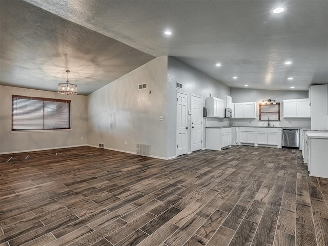 unfurnished living room with dark hardwood / wood-style floors, lofted ceiling, and a chandelier