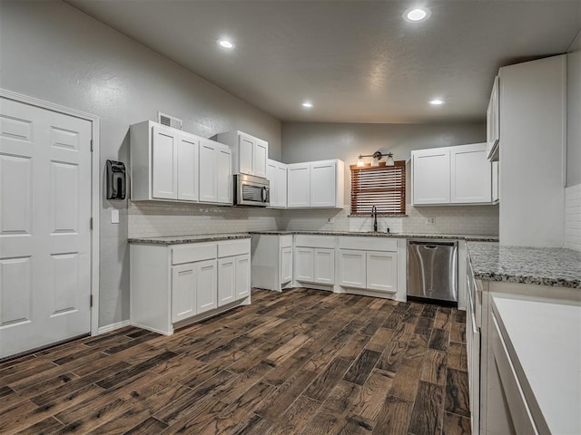 kitchen featuring white cabinets, light stone countertops, stainless steel appliances, and dark hardwood / wood-style floors