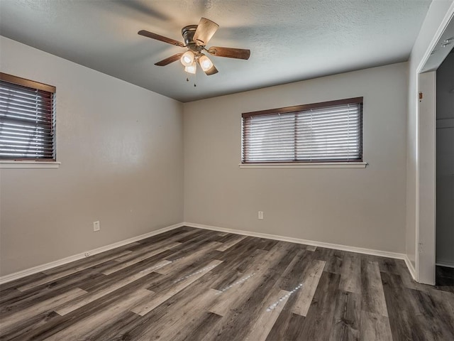 empty room with ceiling fan, dark hardwood / wood-style flooring, and a textured ceiling