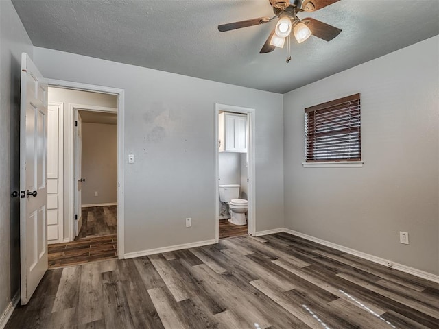 unfurnished bedroom with a textured ceiling, ensuite bath, ceiling fan, and dark hardwood / wood-style floors