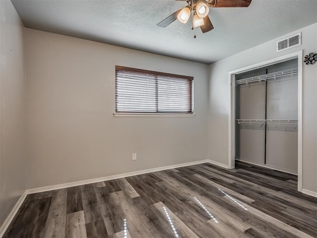 unfurnished bedroom featuring a textured ceiling, a closet, dark wood-type flooring, and ceiling fan