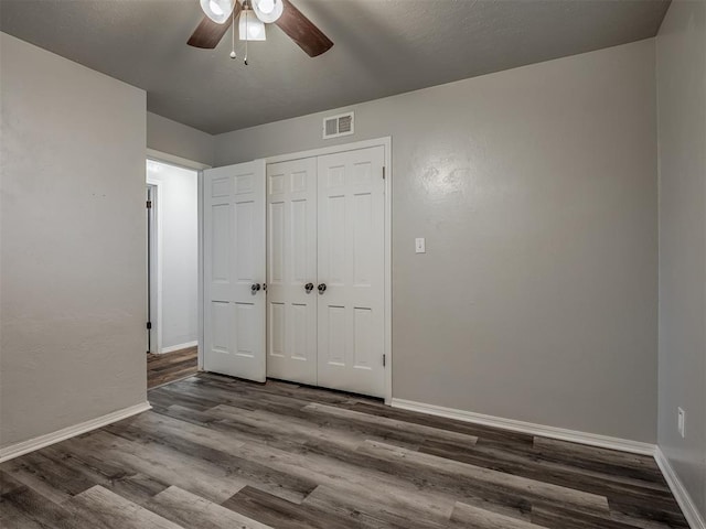 unfurnished bedroom featuring ceiling fan, dark hardwood / wood-style floors, and a closet