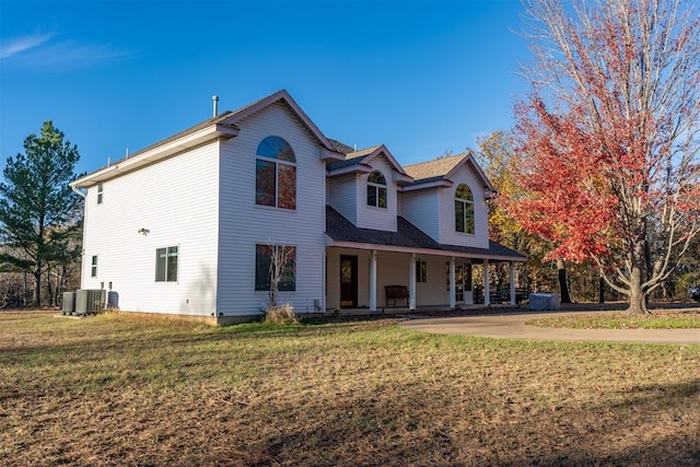 view of front of home featuring cooling unit, covered porch, and a front lawn