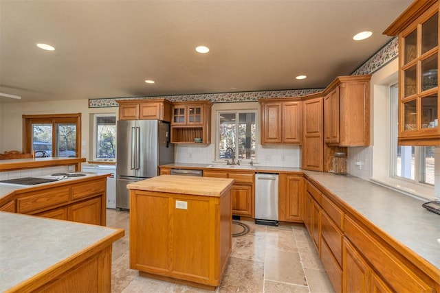 kitchen with sink, appliances with stainless steel finishes, tasteful backsplash, a kitchen island, and butcher block counters