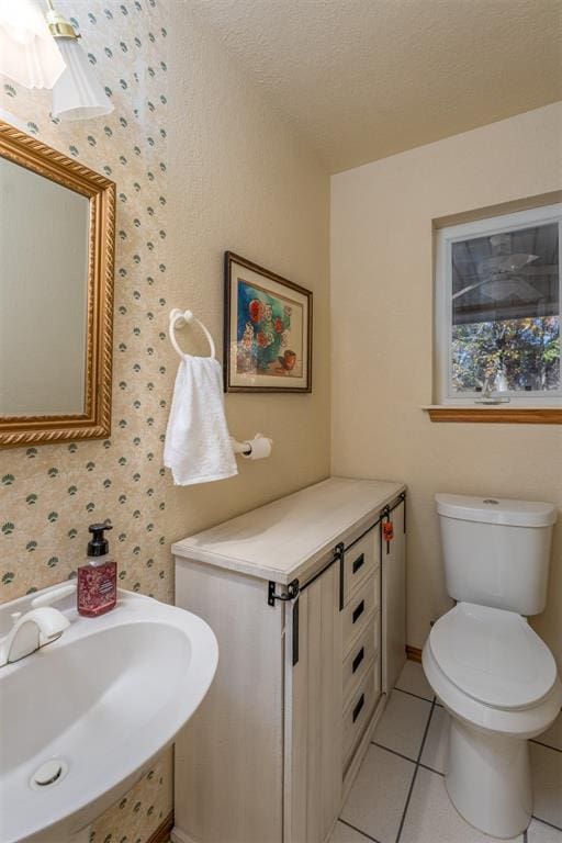 bathroom featuring toilet, sink, a textured ceiling, and tile patterned flooring