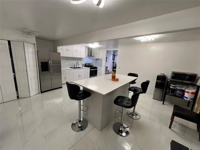 kitchen featuring white cabinetry, sink, stainless steel appliances, a breakfast bar area, and decorative backsplash