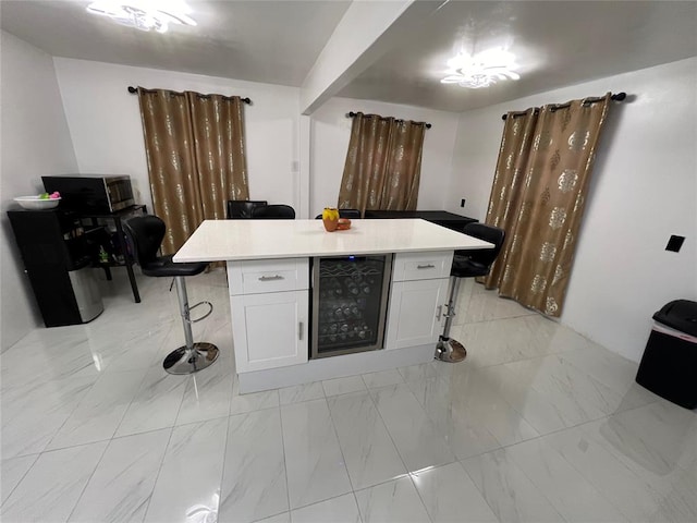 kitchen featuring white cabinets, a center island, a kitchen bar, and beverage cooler