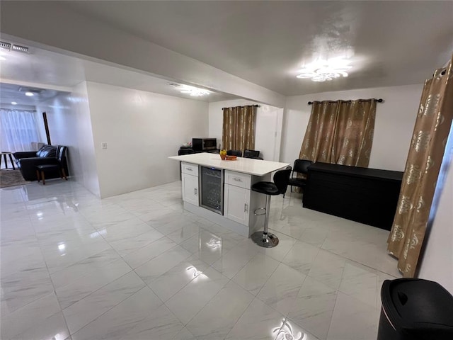 kitchen featuring white cabinets, a center island, wine cooler, and a breakfast bar area