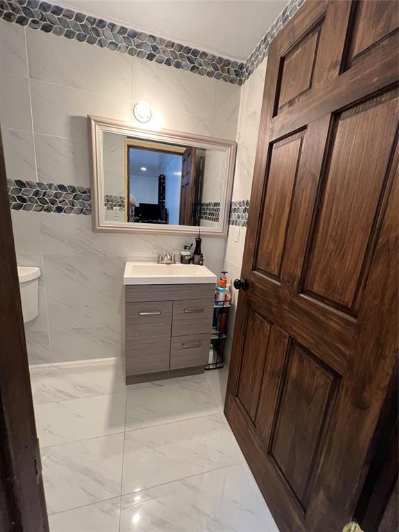 bathroom with vanity, tile walls, and toilet