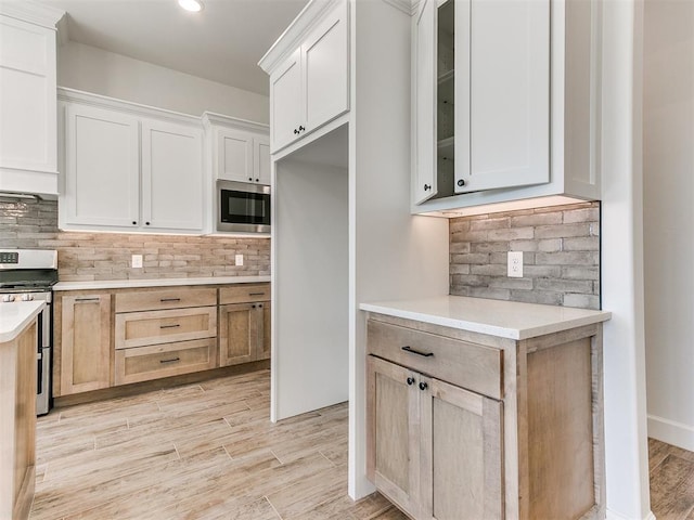 kitchen with light brown cabinets, white cabinets, light wood-type flooring, and appliances with stainless steel finishes