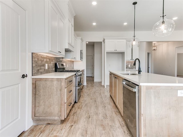 kitchen featuring sink, hanging light fixtures, an island with sink, white cabinets, and appliances with stainless steel finishes