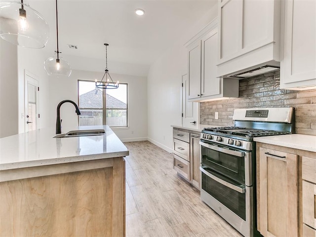 kitchen featuring light brown cabinets, range with two ovens, sink, decorative light fixtures, and white cabinetry