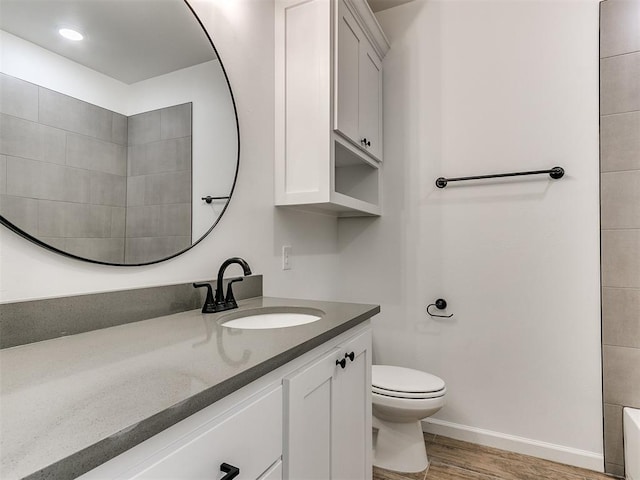 bathroom with a tub, toilet, vanity, and hardwood / wood-style flooring