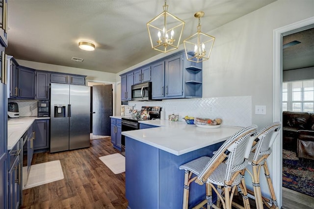 kitchen with hanging light fixtures, stainless steel appliances, a kitchen breakfast bar, dark hardwood / wood-style floors, and kitchen peninsula