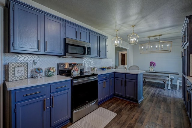 kitchen featuring stainless steel appliances, dark hardwood / wood-style flooring, blue cabinets, kitchen peninsula, and pendant lighting